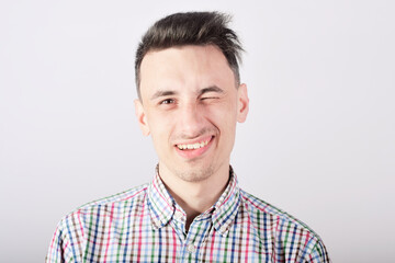 Obraz premium Guy student on a white background smiles and looks at the camera, winks