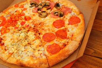 fresh pizza with mushrooms and sausage in a box on the table