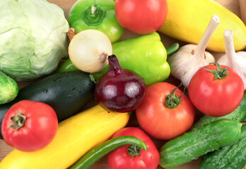 Washed fresh vegetables: tomatoes, cucumbers, zucchini and peppers in large quantities on a white background with water drops. Food background, top view. The concept of natural products.