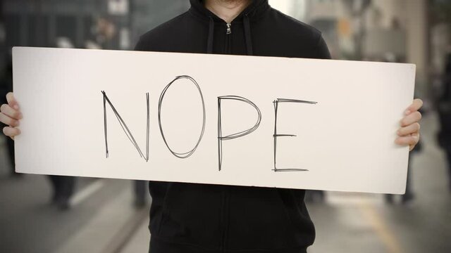 Unknown rioter holds a banner with NOPE text