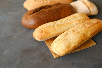 Various loaves of bread. Baked baguette bread and brown loaf of bread on grey table.