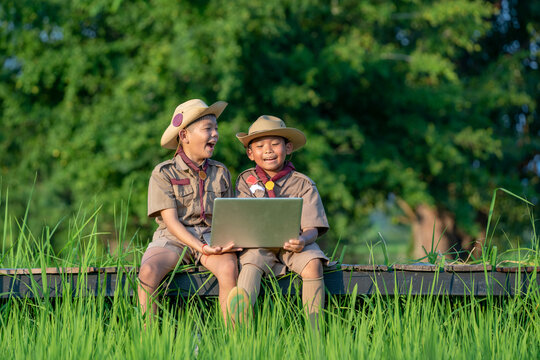 Young American Boy Scouts Use Laptop At Scout Camp During Their Summer Camp.