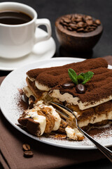 portion of Classic tiramisu dessert and cup of fresh espresso coffee on concrete background