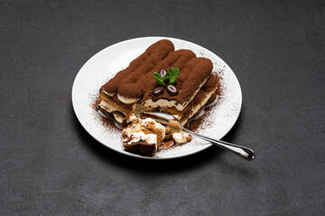 portion of Classic tiramisu dessert on ceramic plate on concrete background