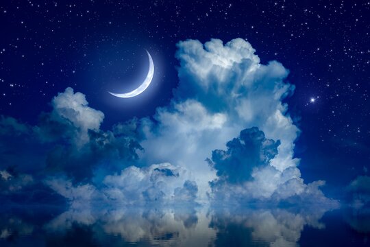 Big crescent moon and clouds in night starry sky is reflected in calm sea. Silence, calmness and serenity