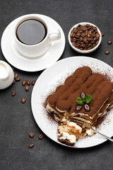 portion of Classic tiramisu dessert and cup of fresh espresso coffee on concrete background