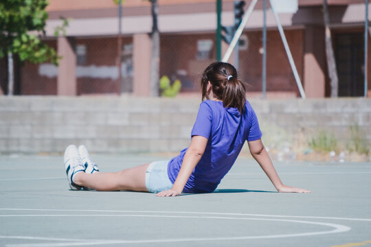 Una chica joven con una camiseta morada se sienta en el suelo en un d&iacute;a soleado de verano