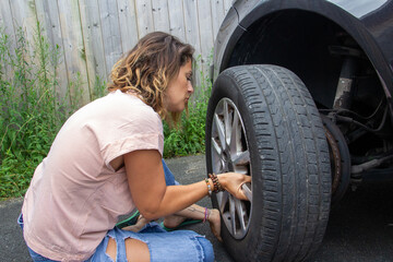 Fototapeta na wymiar Desperate woman because of her punctured car wheel