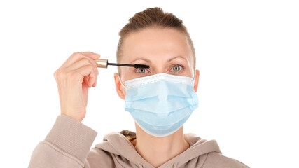 woman in protective mask paint eyelashes with mascara. corona virus prevention and makeup