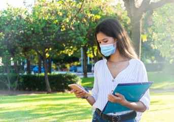 Young woman wearing a medical mask using her phone