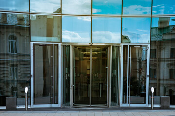 Entrance to modern office building of business city with automatic doors. Skyscraper is designed in modern style. Architecture of building in business district of metropolis. Copyright space