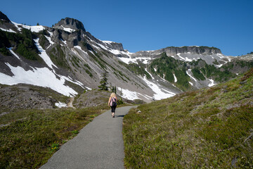 Fototapeta na wymiar Woman hiker walks off into the wilderness in Heather Meadows at Mt. Baker in Washington State