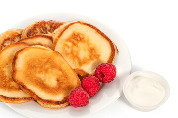 Several pancakes and raspberries on a plate and a little sour cream on a white background. Full depth of field. With clipping path.