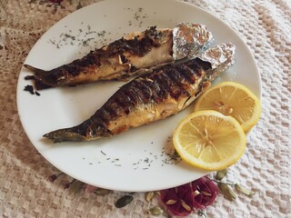 Trucha al grill con rodajas de limón para aderezarlas. Plato de comida tradicional servido en un restaurante de Dragoslavele, Rumanía.