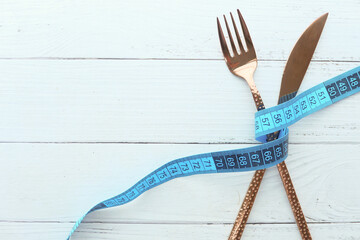 fork with measurement tape on wooden background 