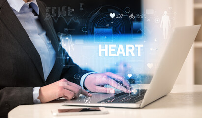 Doctor working a health check with HEART inscription, recording medical test results