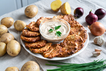 .Potato pancakes, golden, on a white plate. Garlic sauce, fresh herbs, with ingredients.