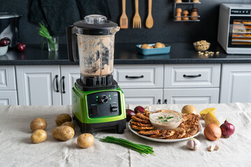 .Potato pancakes, golden, on a white plate. Garlic sauce, fresh herbs, with ingredients. Blende. On the kitchen.