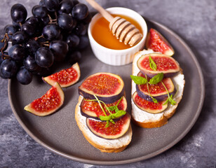 Sandwich with cream cheese, figs and honey served on the gray plate on the concrete background. Healthy food concept.