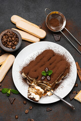 portion of Classic tiramisu dessert and savoiardi cookies on concrete background