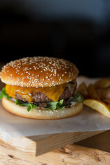 Freshly prepared burger on wooden board with copy space