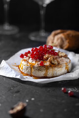 Camembert cheese with fruits and berries on a dark background