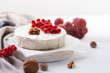 Camembert cheese with fruits, nuts and berries on a white background