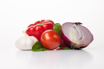 Fresh vegetables on a white background. Ingredients for Gazpacho or tomato sauce: red onion, basil, red pepper, garlic ant tomatoes.  