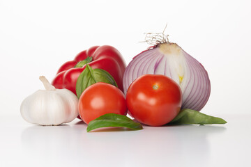 Fresh vegetables on a white background. Ingredients for Gazpacho or tomato sauce: red onion, basil, red pepper, garlic ant tomatoes.  