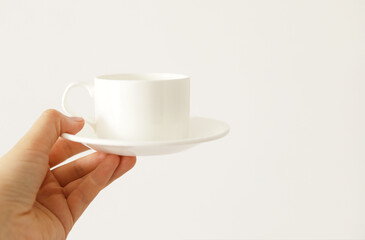 White coffee Cup in a woman's hand on a light background. Selective focus. Breakfast. Copy space