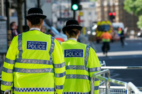 Two Female British Police Officers walking down the street wearing fluorescent jackets