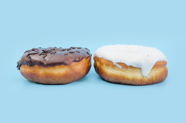 Two delicious donuts with black and white chocolate icing isolated on a blue background.