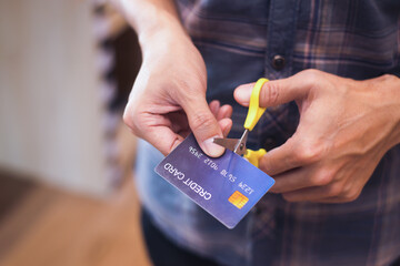 Shopaholic man with shopping bags cutting his credit card , Hands cutting a credit card with scissors,copy space,vintage tone.