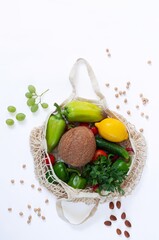 Mesh shopping bag with organic eco vegetables isolated on white background top view