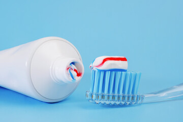toothbrush with toothpaste on it and white toothpaste tube on blue background
