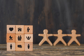 Family concept with icons on wooden cubes, human figures on wooden background side view.