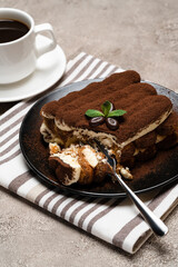 portion of Classic tiramisu dessert and cup of fresh espresso coffee on concrete background