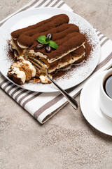 portion of Classic tiramisu dessert and cup of fresh espresso coffee on concrete background