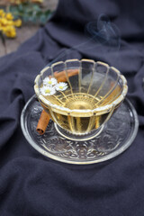 Cup of tea with chamomile flowers on dark purple cotton background