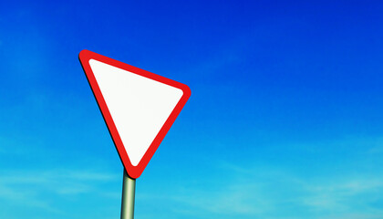 Road sign give way on a metal pole, against a blue sky