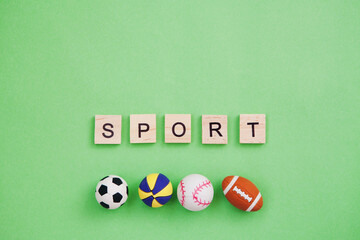 Collection of sport balls and inscription on wooden blocks Sport isolated on green background. Copy space.