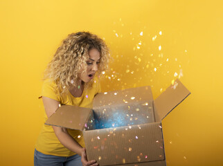 Happy girl receives a package from online shop order. Yellow background.