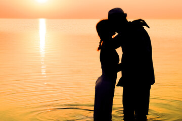 A Happy couple by the sea at sunset on travel silhouette in nature