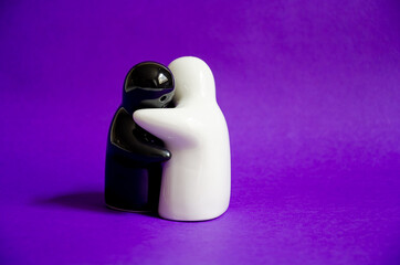 a black and white salt and pepper ghosts hugging each other on a purple background