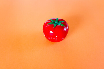 red tomato-shaped timer on orange background. Home related, home staying. Free copy space.