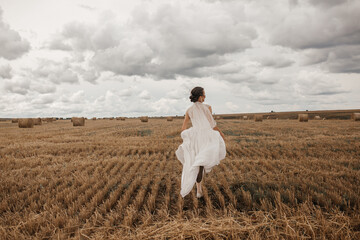 a bride in a wedding dress runs across the field