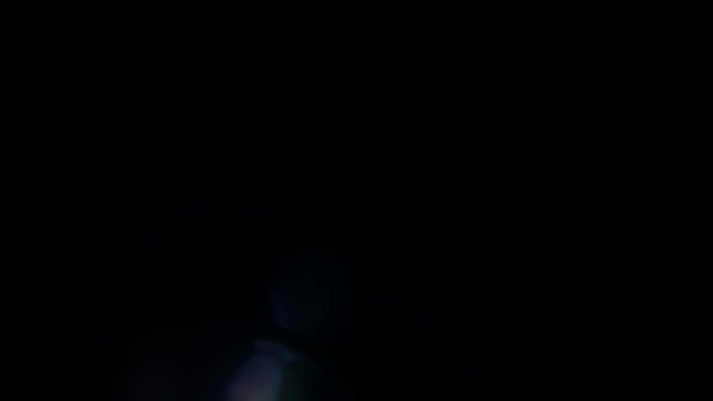 Blue anamorphic lens flares appear in the darkness and disappear again. Straight light beams flicker at the black background of studio. Theme of light transitions for filmmakers