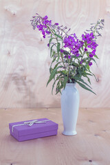 purple gift box and a bouquet of cypress on a wooden background