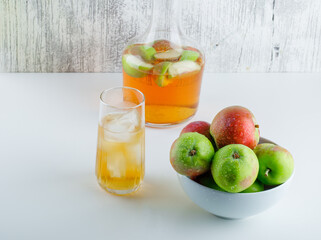Apples in a bowl with drinks high angle view on white and grungy background
