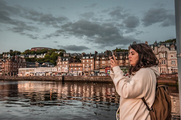 Woman taking a photo with her smartphone of the beach at a coastal town